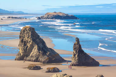 people walking between sea stacks on Bandon Beach, oregon