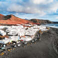 a white-painted village in the mountains on a black sand beach