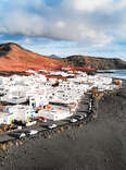 a white-painted village in the mountains on a black sand beach
