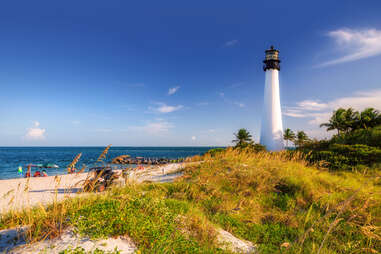 people sitting with umbrellas on the beach beneath the Cape Florida Lighthouse