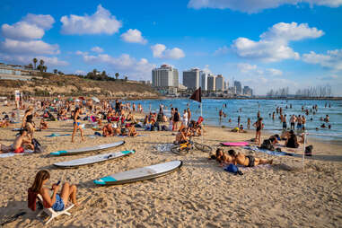 people lounging on a beach with a city in the background