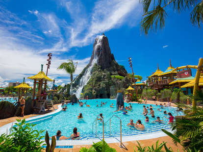 people in the wave pool in front of a giant volcano at a waterpark