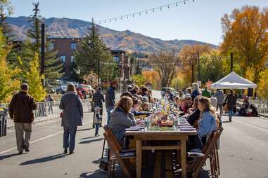 people eating around a table on a street in a mountain town