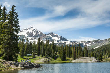 people on a mountainside lake surrounded by trees