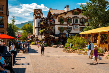 people walking through a flower lined resort town in summer