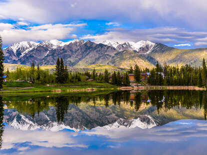 a lakefront wooden cabin beneath a snowy mountain range 