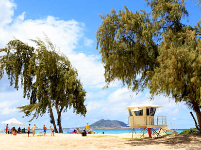 people having a beach day in Hawaii with a lifeguard cabana nearby
