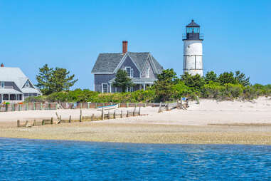 Sandy Neck Lighthouse dotting the blue coast of Cape Cod Bay along a sandy beach