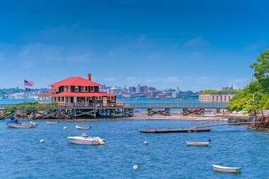 a red-roof building on a dock near a port city