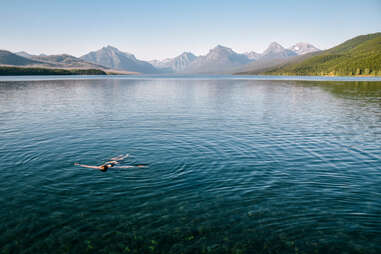 a woman floating in a lake surrounded by mountains