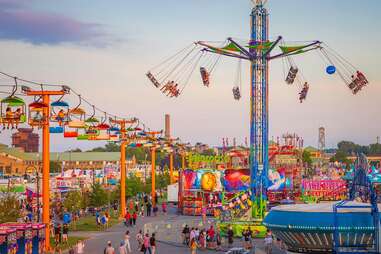 people riding carnival rides and walking the grounds of a state fair