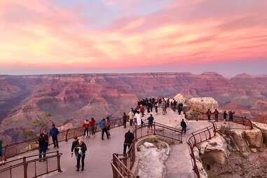 a crowd of people standing on the edge of the grand canyon