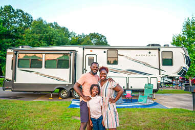 a family posing outside of their RV near a forest