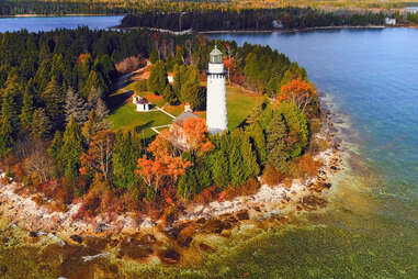 a lakeshore lighthouse surrounded by fall foliage
