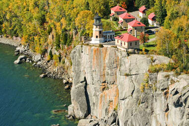 split rock lighthouse on a cliff above fall foliage