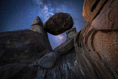 a galaxy seen through large, stacked boulders