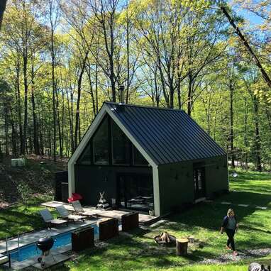 A modern glass and wood cabin with a heated swimming pool