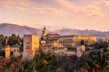 a large castle in front of snow-capped mountains