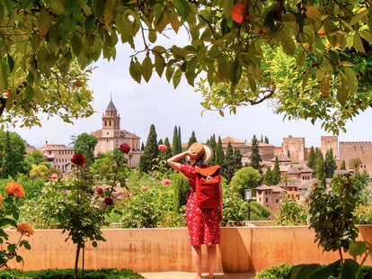 a woman standing in a rose garden looking at a castle