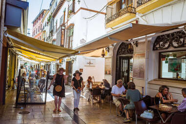 people walking past restaurants and diners on a narrow European street