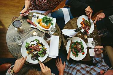 people gathered around small tables eating a nice dinner with wine