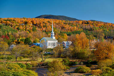 a church spire amongst a mountain of fall foliage