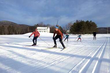 a group of people skiing near a small lodge