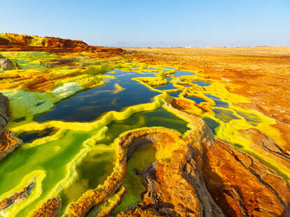 layered pools of colorful acid in the middle of a sweeping desert