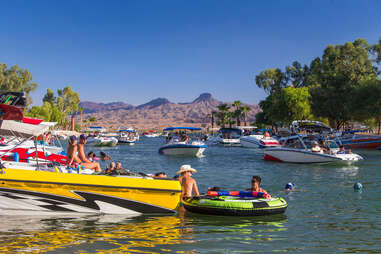 people on boats at a crowded lake with desert mountains in the distance