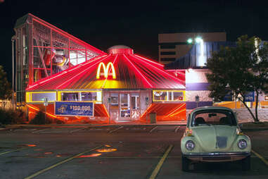 a VW Bug parked in front of a UFO-shaped McDonald's