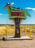 a sign for roswell, new mexico with a flying saucer on it in the desert
