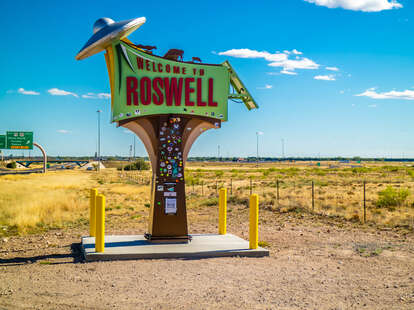 a sign for roswell, new mexico with a flying saucer on it in the desert