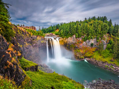 a hotel at the top of a waterfall surrounded by trees