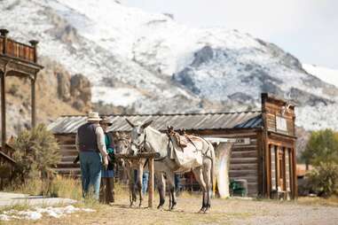 two men tending to donkeys in a mountainside ghost town