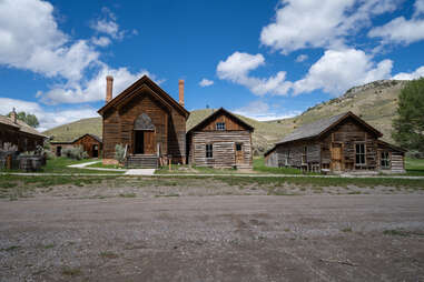 abandoned wooden buildings at the base of a mountain range