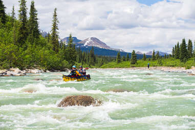 people canoeing down a whitewater river with mountains in the distance