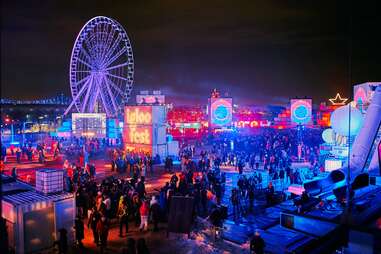 people at a festival in front of a Ferris wheel