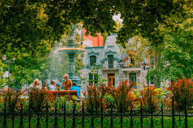 people sitting on a bench in front of townhouses