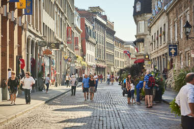 people walking down a cobblestone shopping district of old montreal