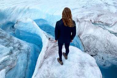 a woman walking near an ice crevasse