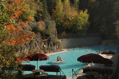 people soaking in a hot spring beneath fall foliage