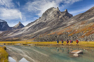 five backpackers hiking past mountains and a river