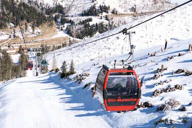 a gondola on a ski lift above snowy mountains