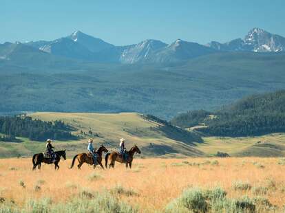 people riding on horseback through a valley