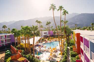 people at a colorful hotel pool surrounded by palm trees