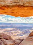 Panoramic view of famous Mesa Arch, iconic symbol of the American West, illuminated golden in beautiful morning light on a sunny day with blue sky and clouds, Canyonlands National Park, Utah, USA