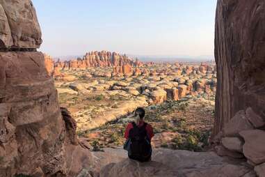 a woman gazing out across a large high desert filled with slender, towering rock formations