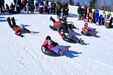 people tubing down a snowy hill