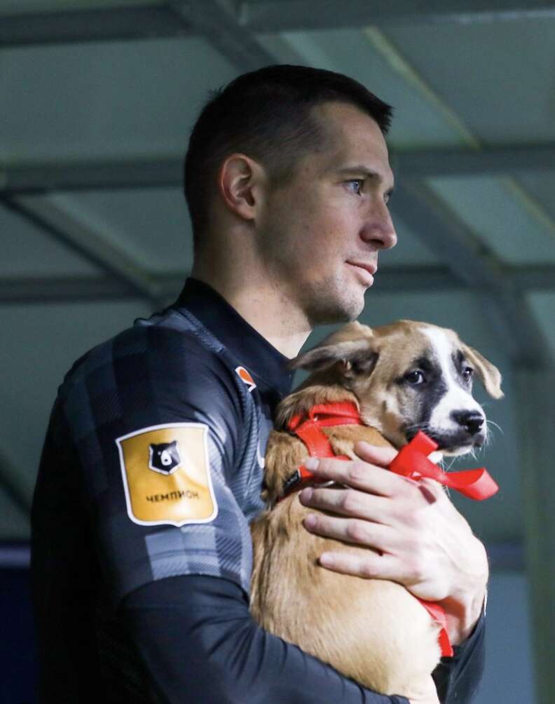 soccer player carrying shelter puppy