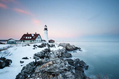 New England's iconic Portland Head Lighthouse on the edge of a snow covered coast in winter